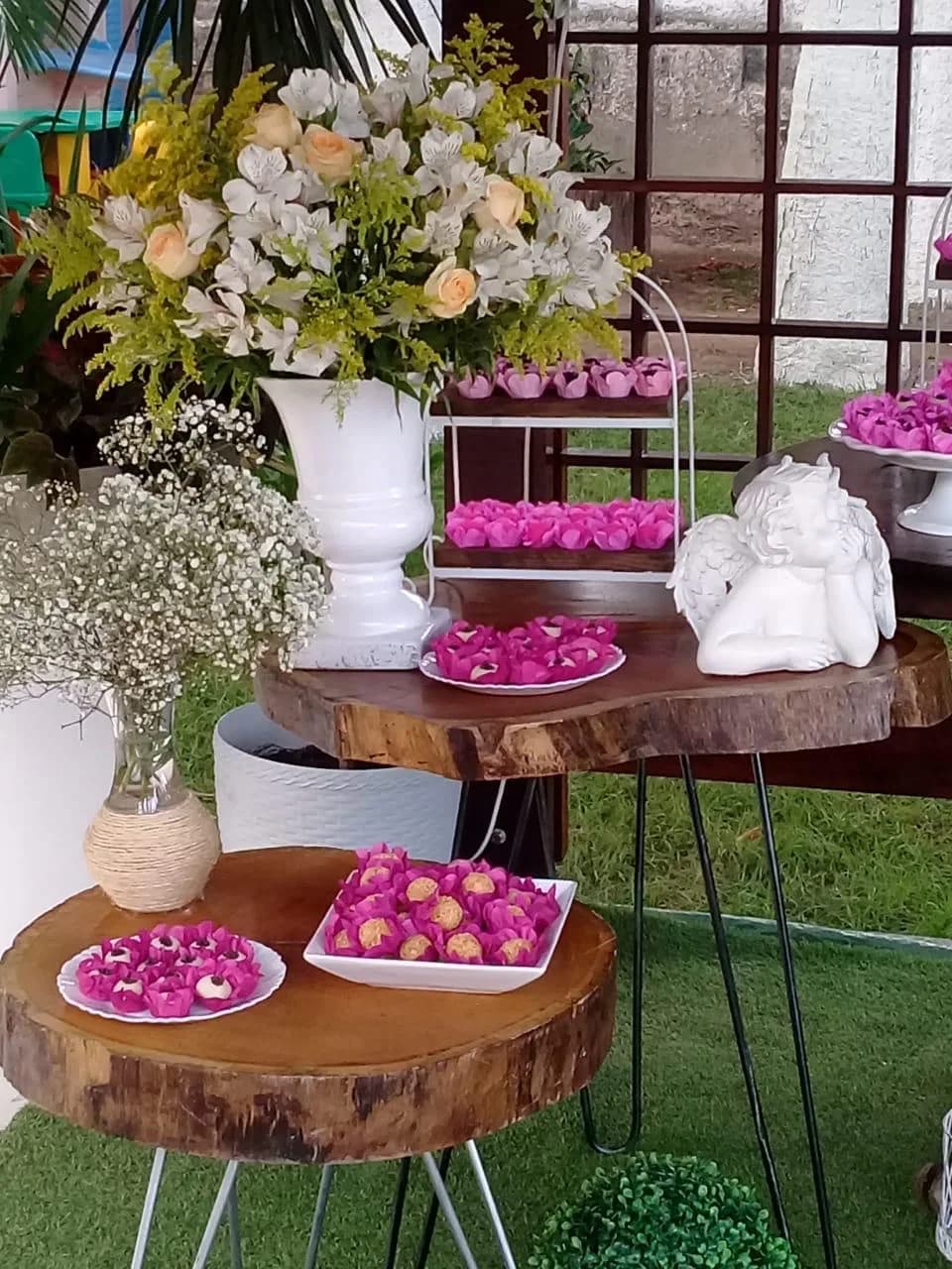 Arranjos de flores e doces servidos sobre tábua de madeira